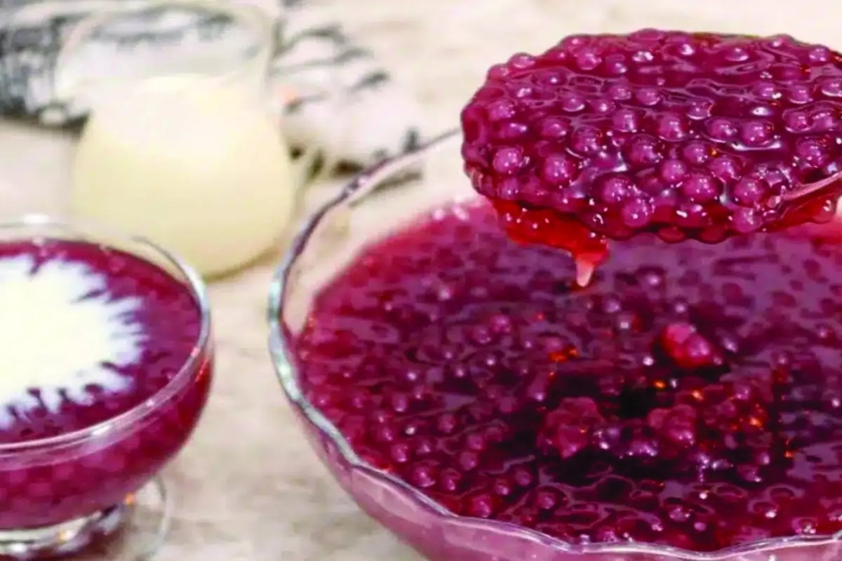 Sagu de vinho tinto cremoso em taças de vidro com creme de baunilha e uvas frescas